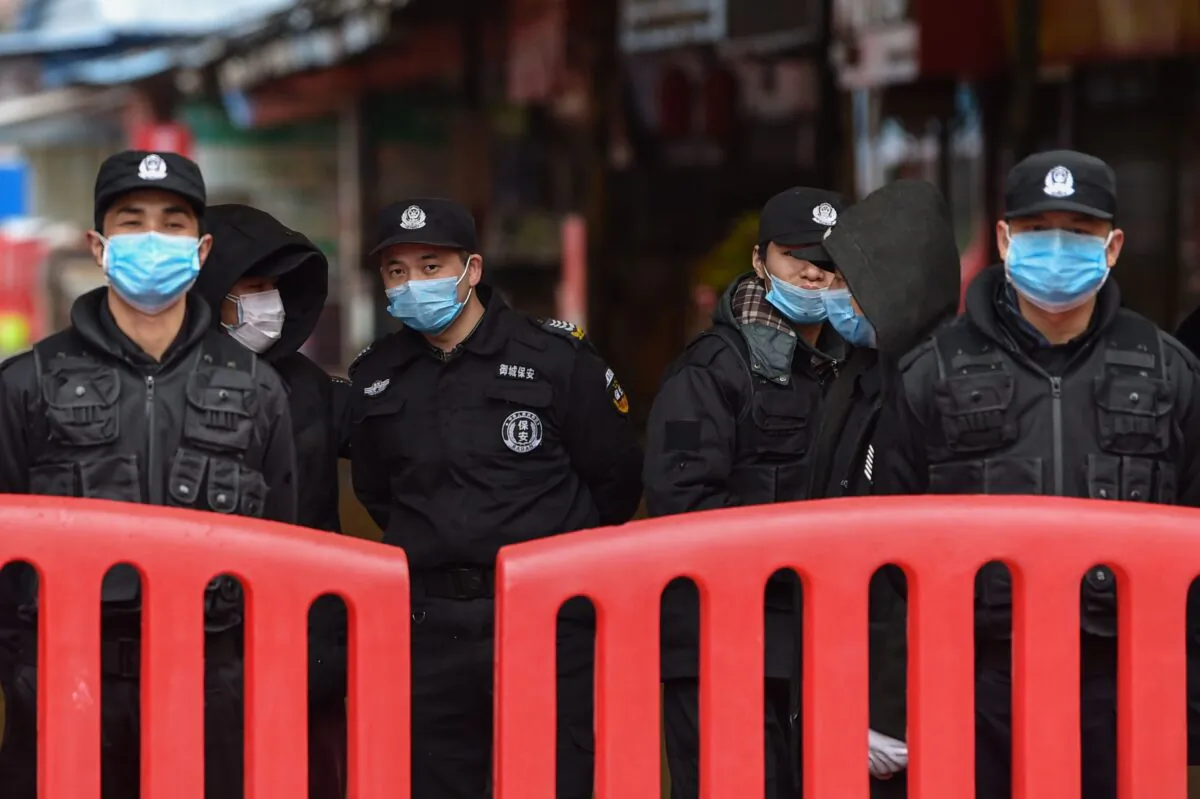 Police officers and security guards stand outside the Huanan Seafood Wholesale Market in Wuhan on Jan. 24, 2020. (HECTOR RETAMAL/AFP via Getty Images)