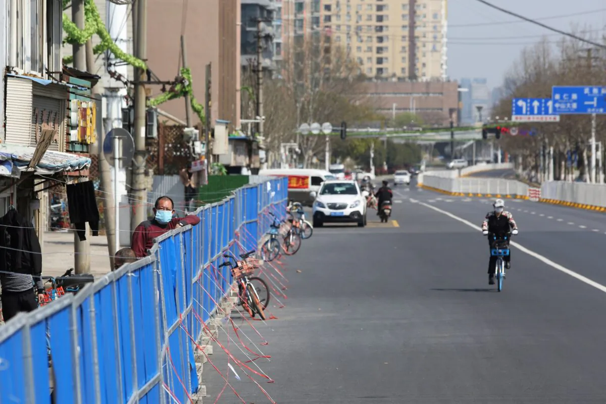 A man looks over a barrier set up to prevent people from entering or leaving a residential compound in Wuhan, China, on March 17, 2020. (STR/AFP via Getty Images)