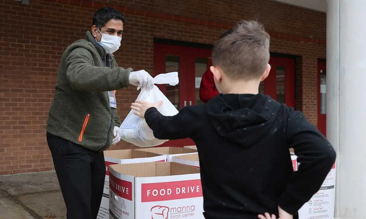 Montgomery County Public Schools Special Needs Bus Attendant Bhavin Savla helps distribute bags of food donated by Manna Food Center at Quince Orchard High School as part of a program to feed children while schools are closed due to the coronavirus, in Gaithersburg, Maryland, on March 20, 2020. (Chip Somodevilla/Getty Images)