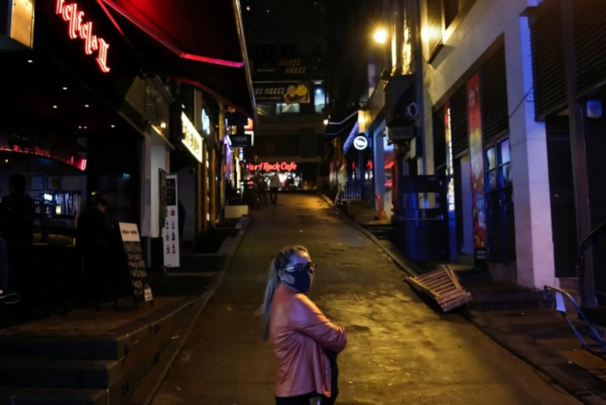 A woman stands outside an almost empty pubs area, following the novel coronavirus disease (COVID-19) outbreak, at Lan Kwai Fong, a popular nightlife destination in Central, Hong Kong, China, on March 20, 2020. (Tyrone Siu/Reuters)