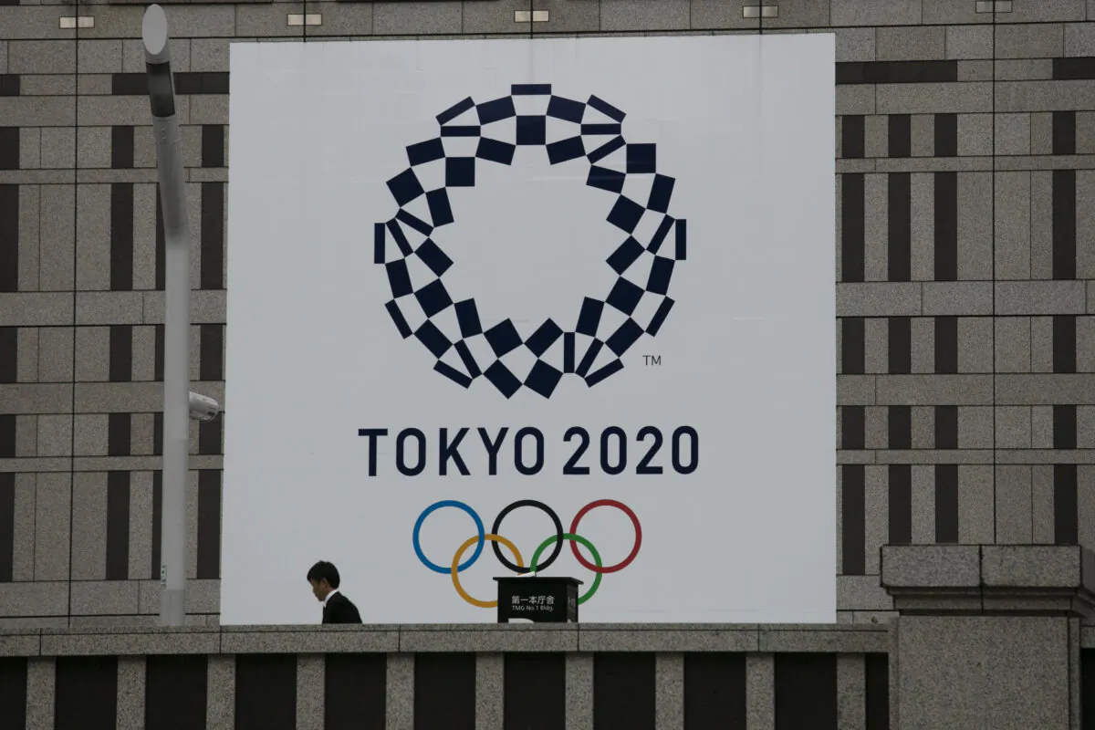 A man walks past a large banner promoting the Tokyo 2020 Olympics in Tokyo, on March 23, 2020. (Jae C. Hong/AP Photo)