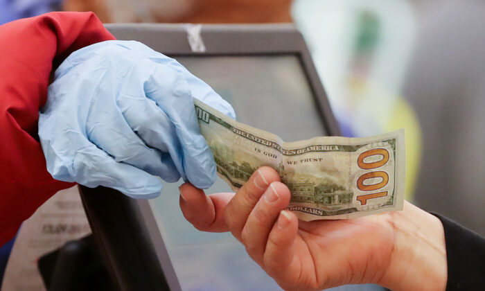 A woman pays cash while wearing gloves at a supermarket in Los Angeles on March 19, 2020. (Mario Tama/Getty Images)