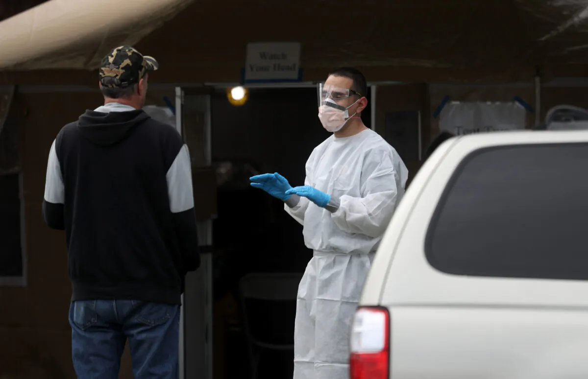 A firefighter screens a man that is waiting in line to get a COVID-19 test at a free public testing station in Hayward, California, on March 24, 2020. (Justin Sullivan/Getty Images)