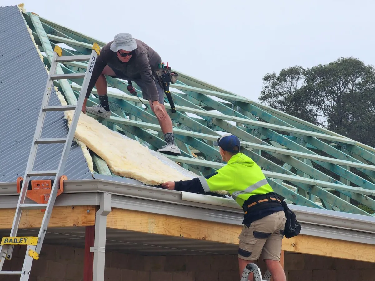 Two roofers position a piece of insulation on a roof in Albany, Western Australia, on Aug. 23, 2024. (Susan Mortimer/The Epoch Times)