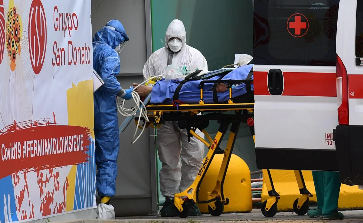 Medical workers stretch a patient from an Italian Red Cross ambulance into an intensive care unit set up in a sports center outside the San Raffaele hospital in Milan, on March 23, 2020. (Miguel Medina/AFP via Getty Images)