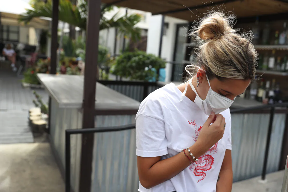 Pia Rodriguez waits for a bus as she leaves the Beach Plaza hotel for another hotel in Miami in Miami Beach, Florida, on March 23, 2020. (Joe Raedle/Getty Images)