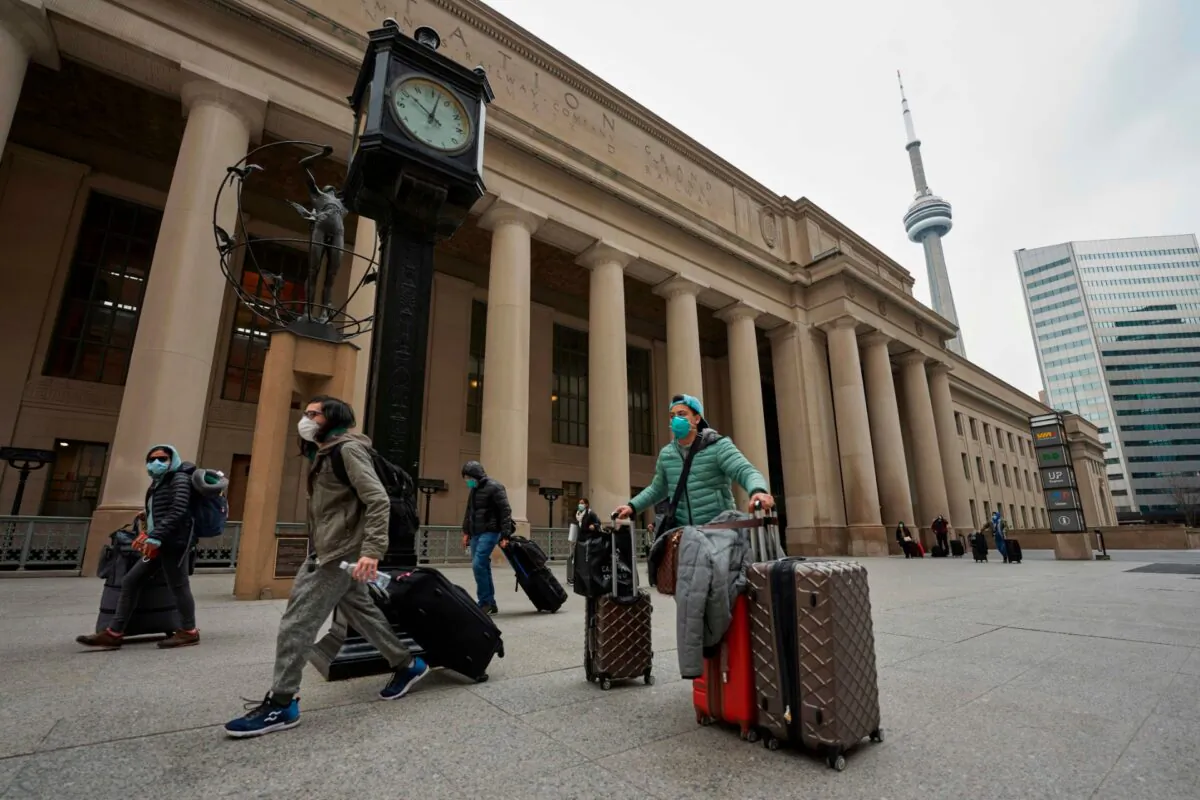 Travellers in masks leave Union Station in Toronto, Ontario, Canada, on March 24, 2020. (Photo by Geoff Robins / AFP  via Getty Images)
