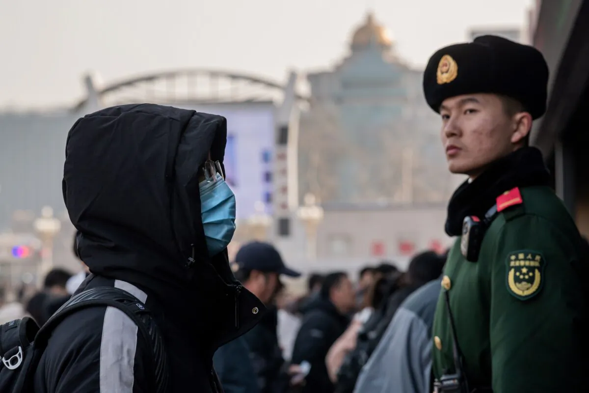 A man wearing a protective mask arrives at Beijing railway station next to a paramilitary police officer (R) as he heads home for the Lunar New Year on Jan. 21, 2020. (Nicolas Asfouri/AFP via Getty Images)