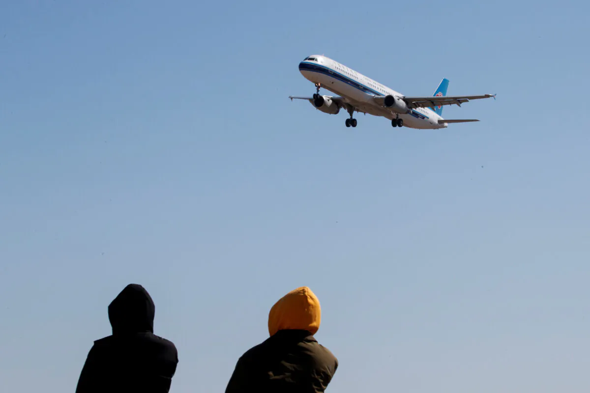 People watch a plane of China Southern Airlines land at Beijing Capital International in Beijing on March 13, 2020. (Thomas Peter/Reuters)