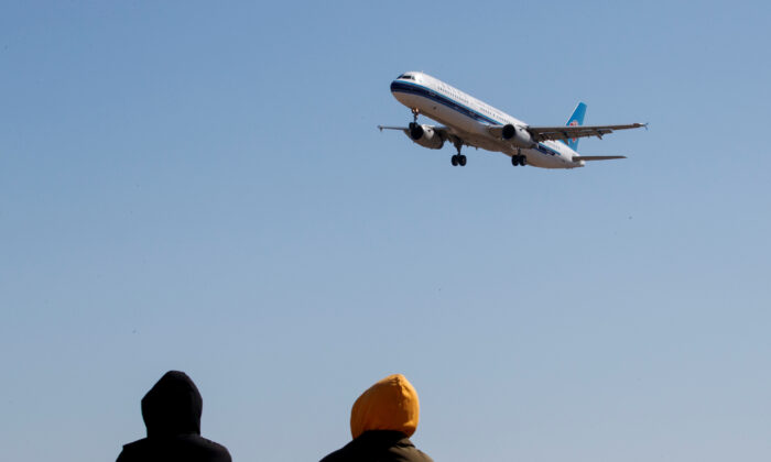 People watch a plane of China Southern Airlines land at Beijing Capital International in Beijing on March 13, 2020. (Thomas Peter/Reuters)