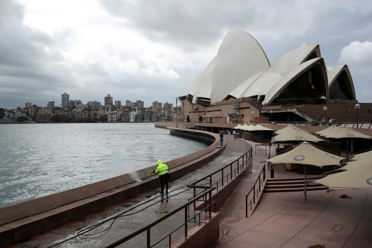 A worker cleans the waterfront area of the Sydney Opera House, in the wake of New South Wales implementing measures shutting down non-essential businesses and moving toward harsh penalties to enforce self-isolation, in Australia on March 26, 2020. (Loren Elliott/Reuters)