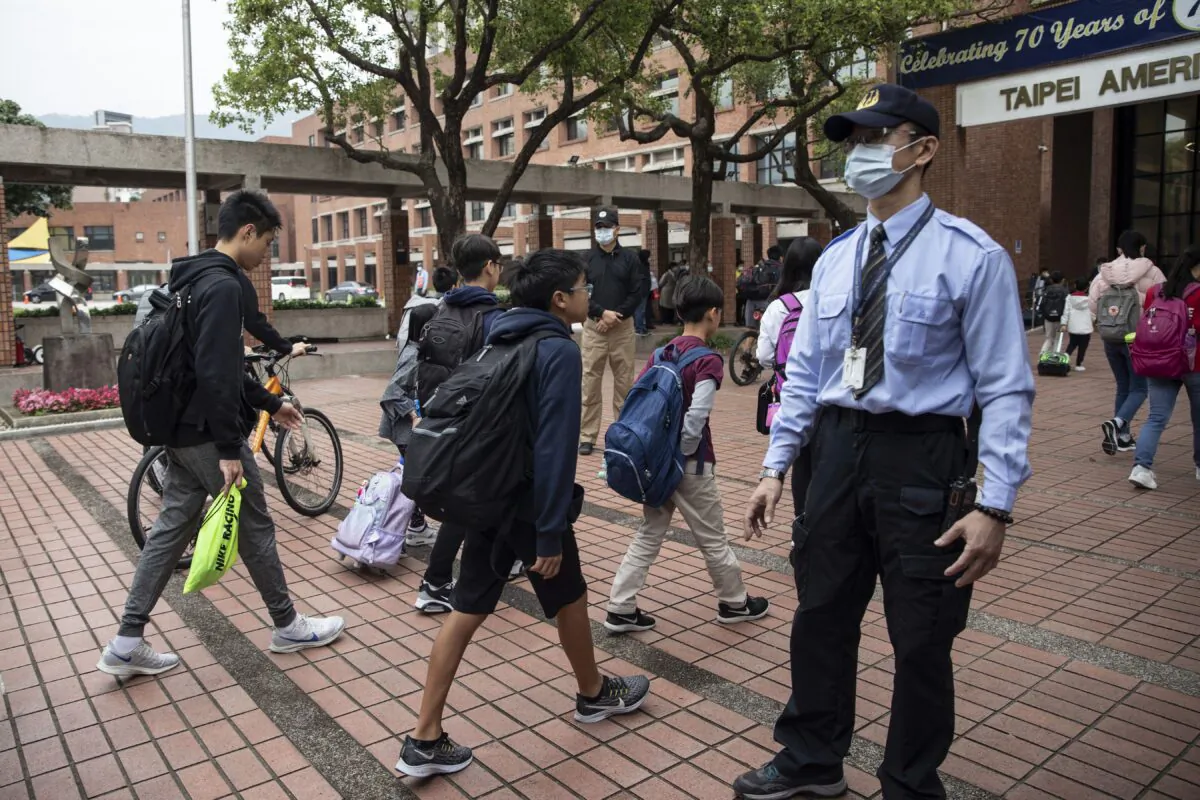Students enter the Taipei American School in Taipei, Taiwan, on March 18, 2020. Taiwan, Singapore, and Hong Kong have had more success in battling the COVID-19 pandemic that other jurisdictions can learn from. (Paula Bronstein/Getty Images)
