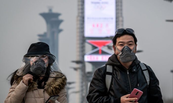 People wearing face masks walk at the Olympic park in Beijing on March 24, 2020. (Nicolas Asfouri/AFP via Getty Images)
