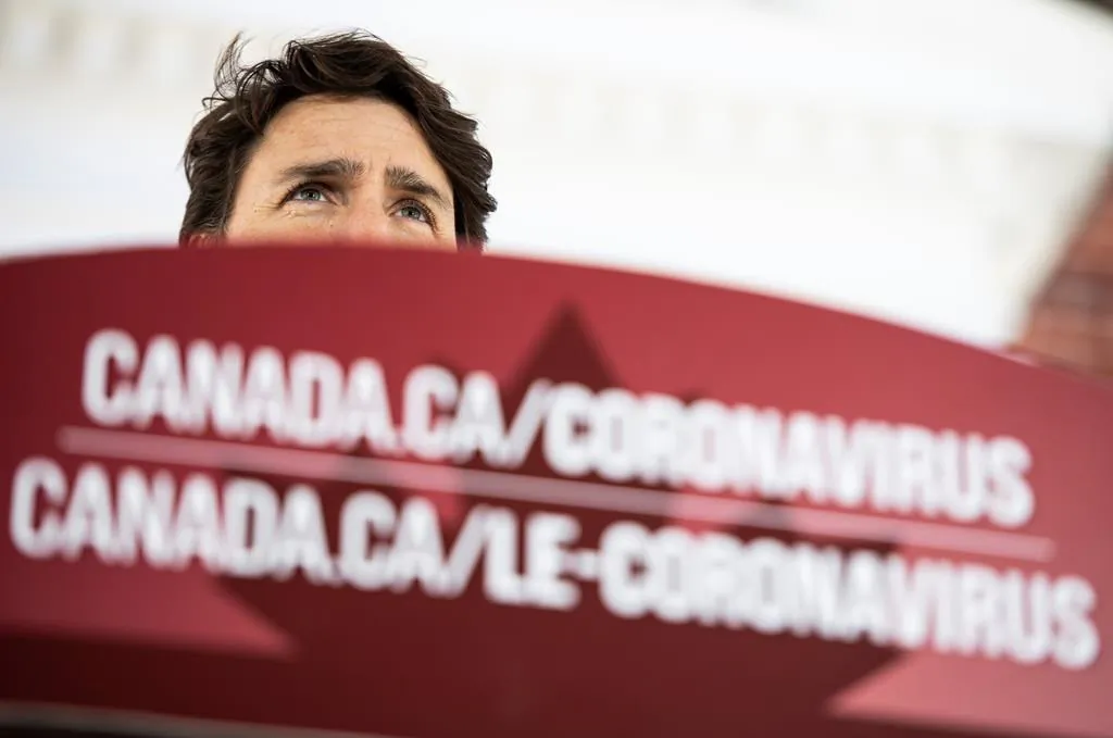 Prime Minister Justin Trudeau speaks from behind a podium bearing the hyperlink to a federal government website about the coronavirus disease during a press conference about COVID-19 in front of his residence at Rideau Cottage in Ottawa, on March 22, 2020. (The Canadian Press/Justin Tang)