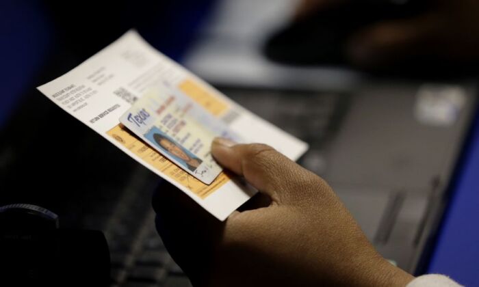 An official checks a voter's photo identification at an early voting polling site in Austin, Texas, on Feb. 26, 2014. (Eric Gay/AP Photo)