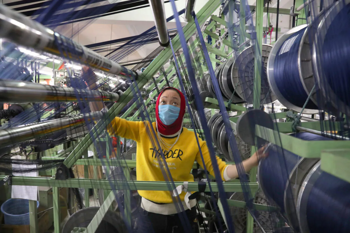 An ethnic minority employee wearing a face mask works on a production line manufacturing elastic fabric products, as the country is hit by an outbreak of the novel coronavirus disease (COVID-19), in Nantong, Jiangsu Province, China, on (March 26, 2020. China Daily via Reuters)