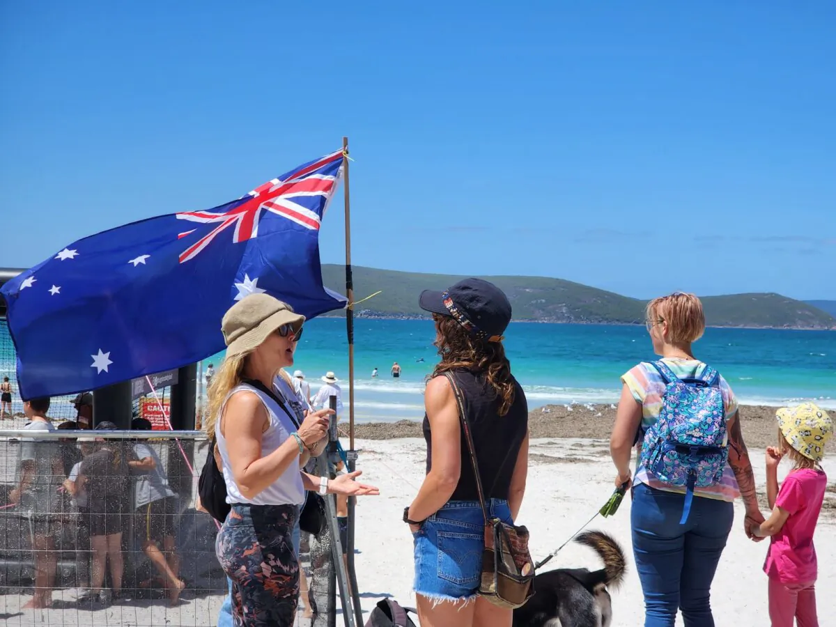 People stand near an Australian Flag at an Australia Day event in Albany, Western Australia, on Jan. 26, 2024. (Susan Mortimer/The Epoch Times)