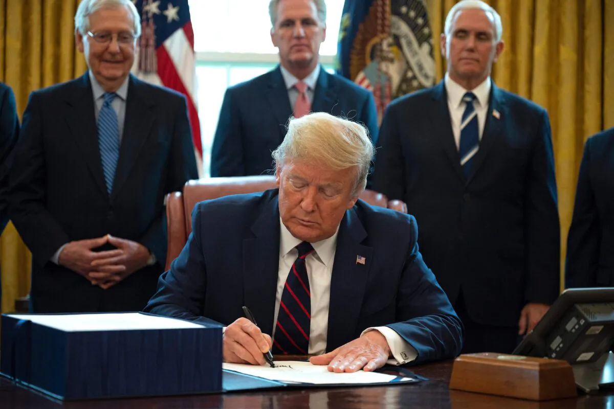 President Donald Trump signs the CARES act, a $2.2 trillion rescue package to provide economic relief amid the coronavirus outbreak, at the Oval Office of the White House on March 27, 2020. (Jim Watson/AFP via Getty Images)