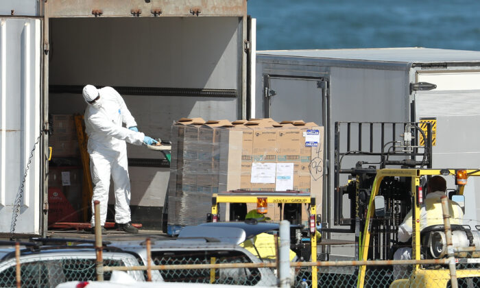 Workers are seen unloading supplies from a truck wearing protective equipment to be loaded onto the MSC Magnifica berthed at the Fremantle Passenger Terminal in Fremantle, Australia, on March 24, 2020. (Paul Kane/Getty Images)