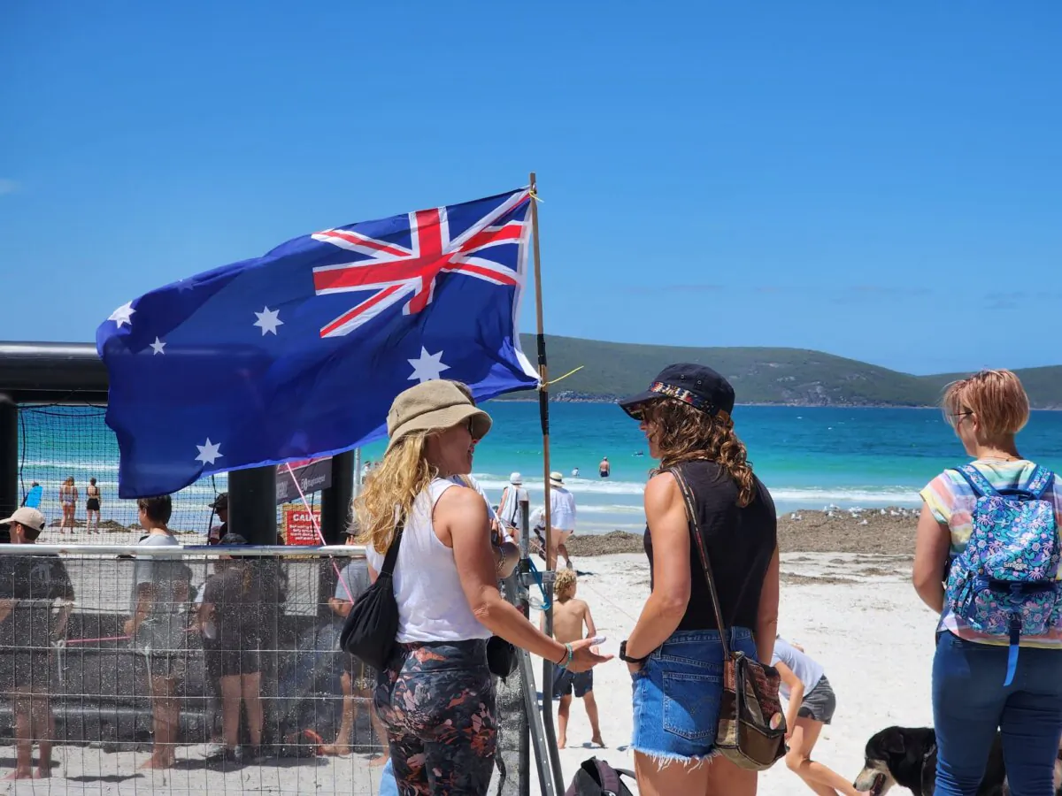 People stand near an Australian flag at an Australia Day event in Albany, Western Australia, on Jan. 26, 2024. (Susan Mortimer/The Epoch Times)