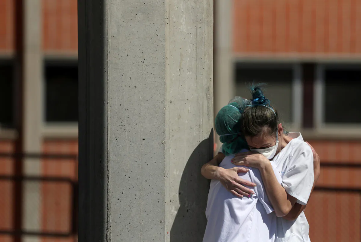 Medical wokers hug each other outside the emergency rooms at Severo Ochoa Hospital during the COVID-19 outbreak in Leganes, Spain on March 26, 2020. (Susana Vera/Reuters)