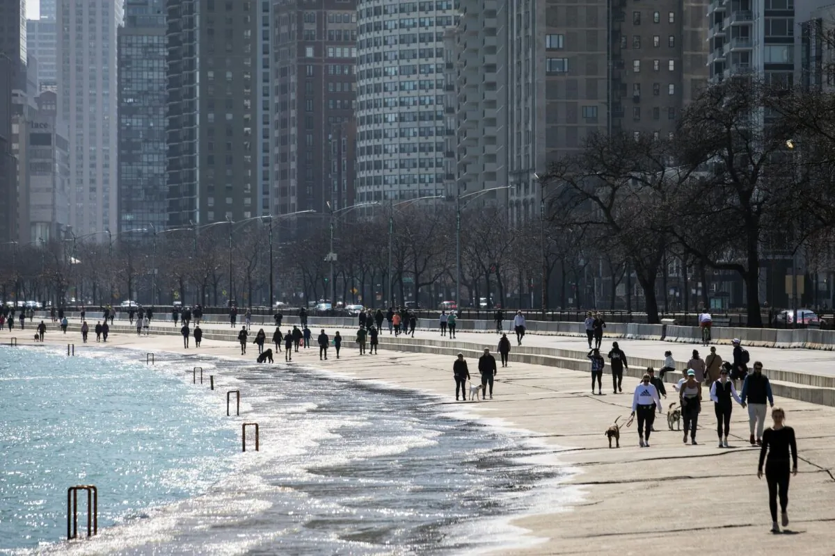 Residents enjoy the warm weather with a stroll along the Lakefront Trail near Oak Street Beach, on March 25, 2020, in Chicago, Illi., despite a stay-at-home order from Illinois Gov. J.B. Pritzker during the CCP virus pandemic. (Ashlee Rezin Garcia/Chicago Sun-Times via AP)