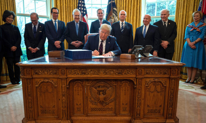 President Donald Trump signs the CARES act, a $2.2 trillion rescue package to provide economic relief amid the CCP virus outbreak, at the Oval Office of the White House on March 27, 2020. (Jim Watson/AFP via Getty Images)