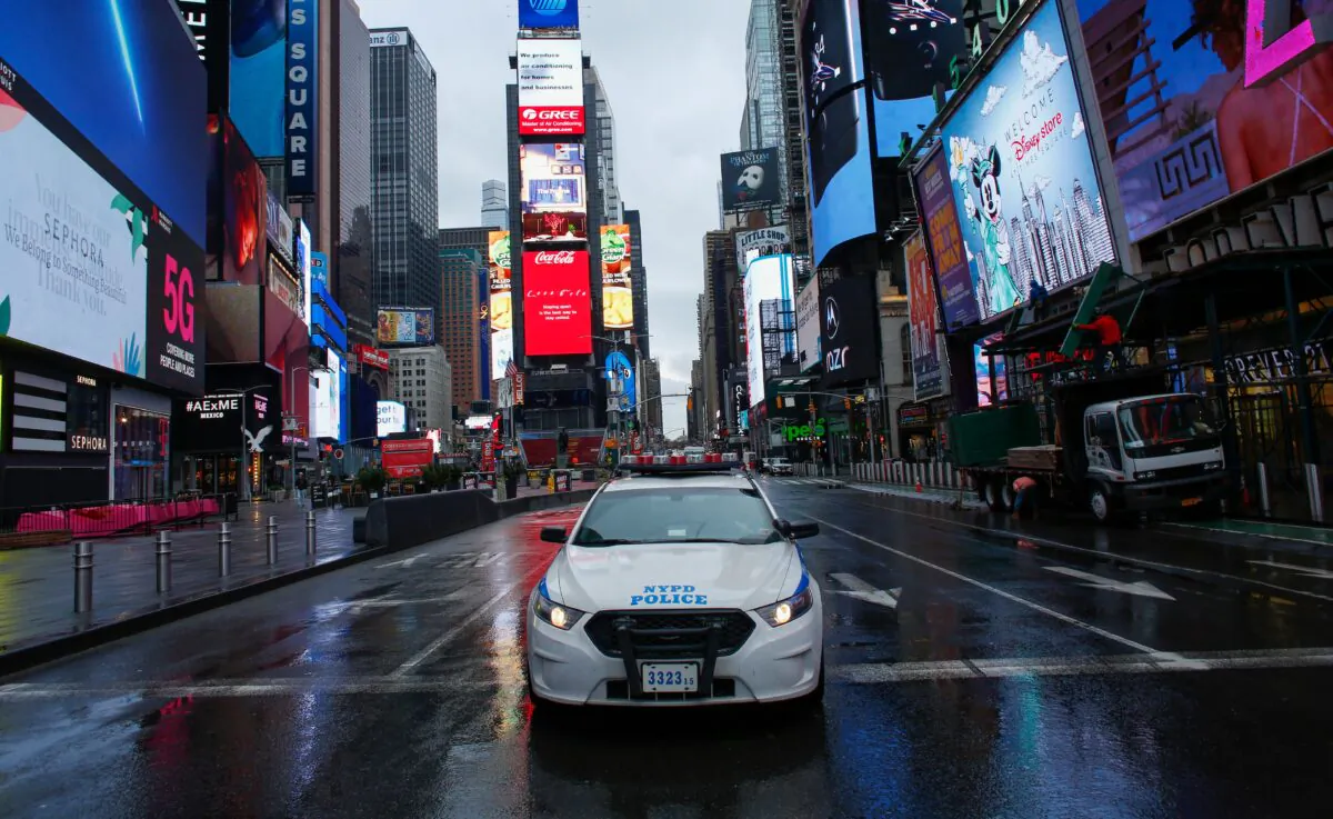 A NYPD car drives by Times Square as rain falls in New York City on March 28, 2020. (Kena Betancur/AFP via Getty Images) 