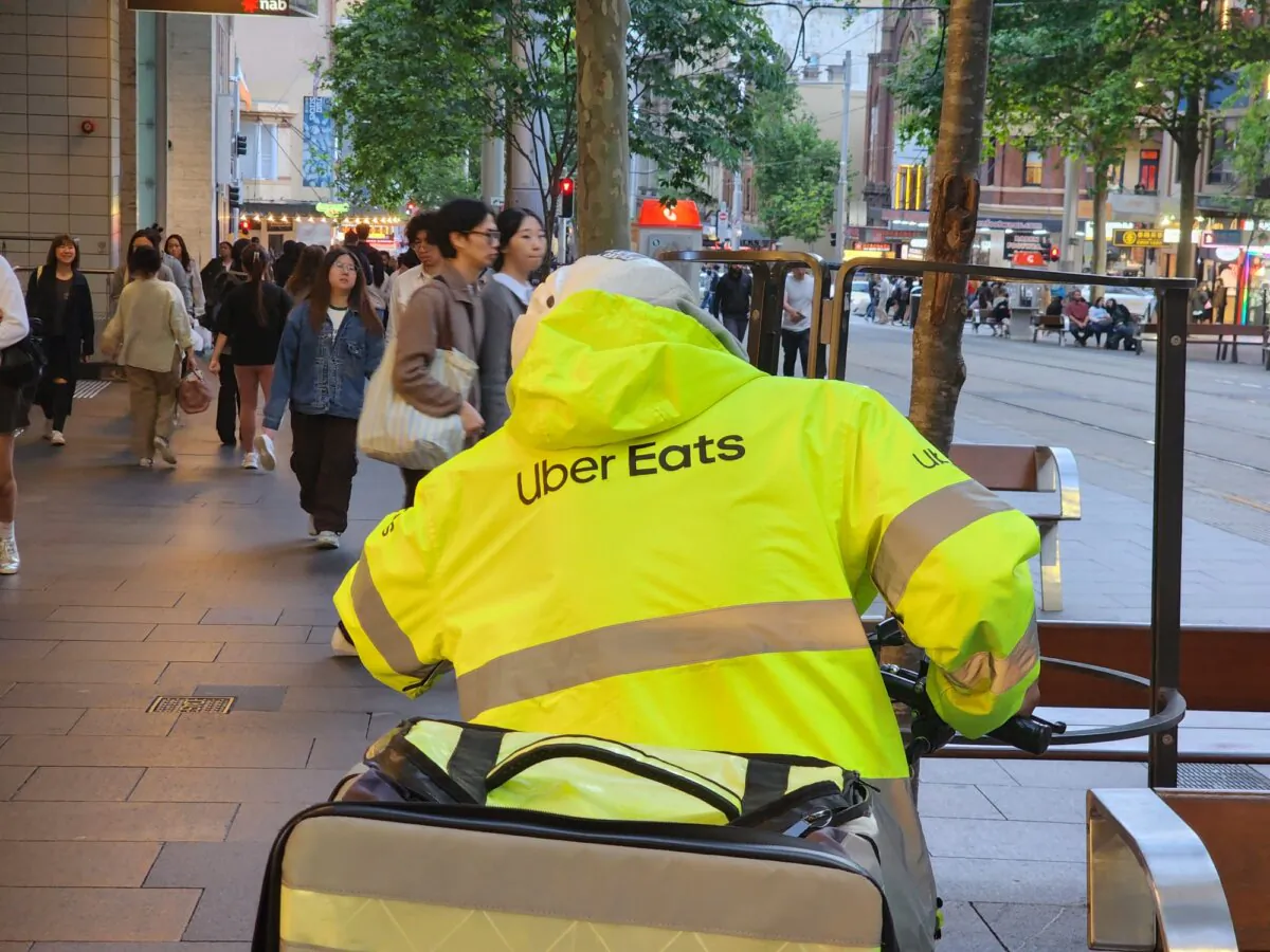 An Uber Eats food delivery worker rides a scooter in Sydney, Australia, on Oct. 25, 2024. (Susan Mortimer/The Epoch Times)