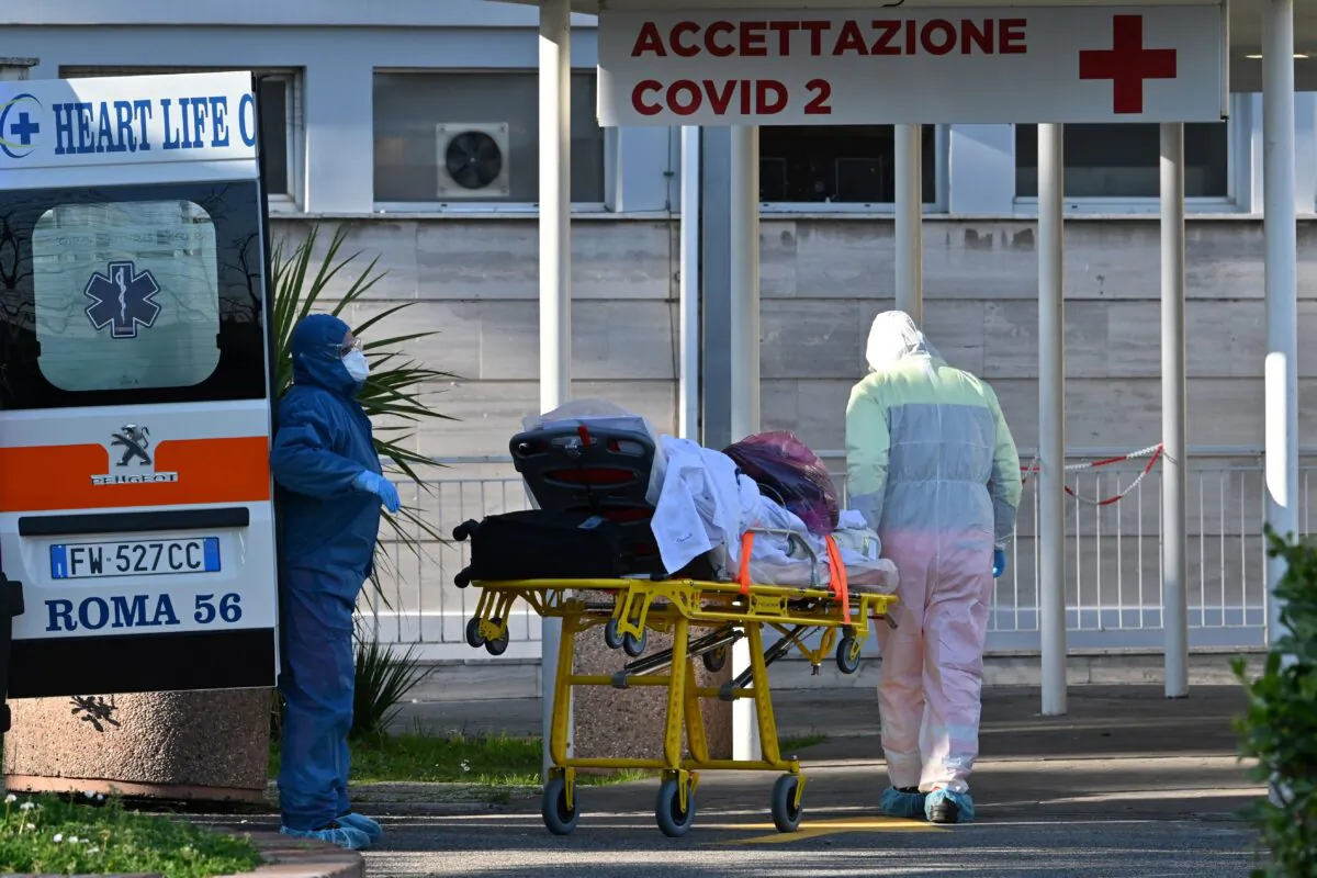 Male nurses wearing a face mask and overalls bring a patient on a stretcher into the newly built Columbus Covid 2 temporary hospital to fight the new coronavirus infection at the Gemelli hospital in Rome on March 16, 2020. (Andreas Solaro/ AFP via Getty Images)