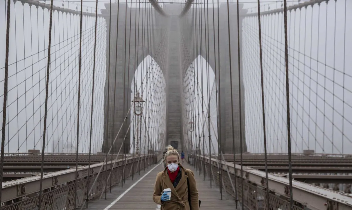 A woman wearing a mask walks the Brooklyn Bridge in the midst of the coronavirus (COVID-19) outbreak in New York City on March 20, 2020. (Victor J. Blue/Getty Images)