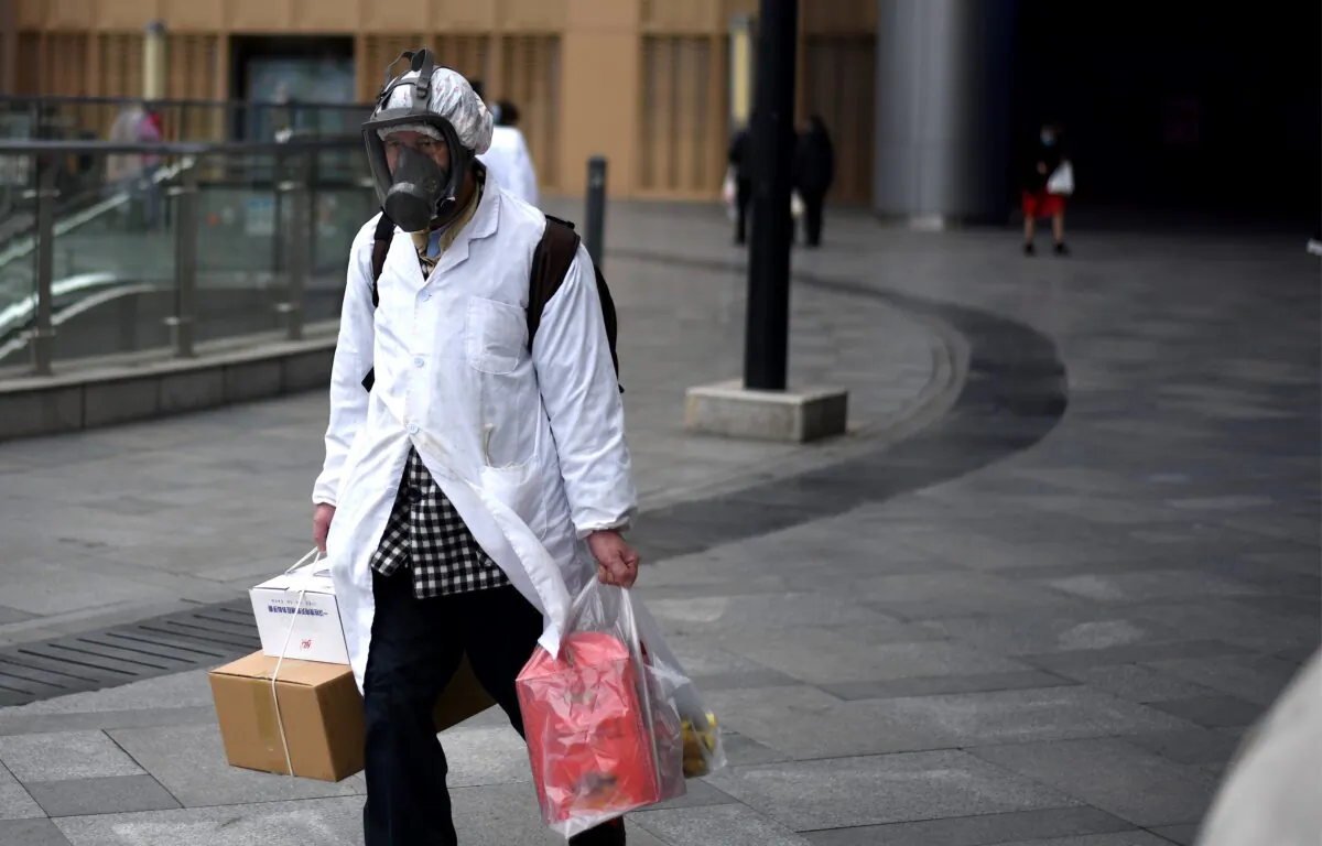 A man wearing a mask carries items he bought at a supermarket in Wuhan, China on March 30, 2020. (NOEL CELIS/AFP via Getty Images)