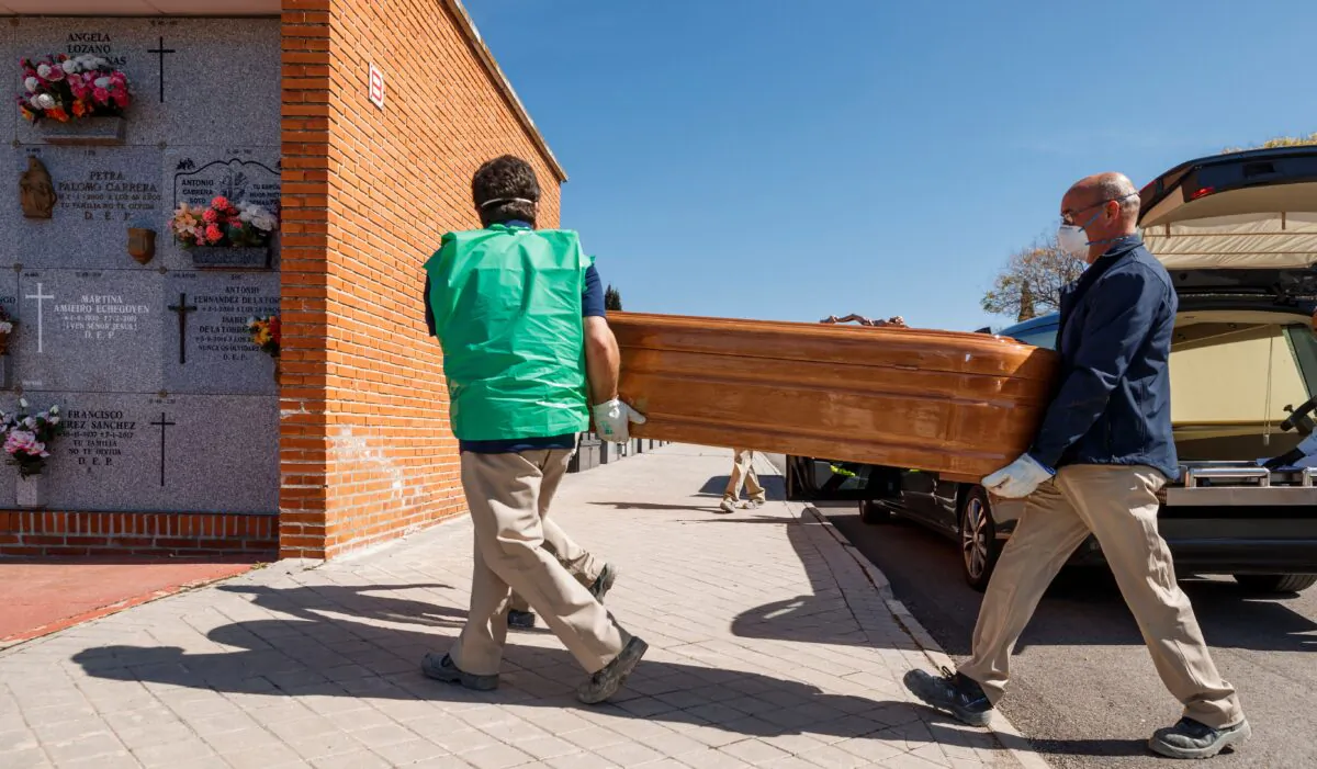 Mortuary employees wearing masks carry the coffin of a COVID-19 victim during a burial at the Fuencarral cemetery in Madrid on March 29, 2020. (Baldesca Samper/AFP via Getty Images)