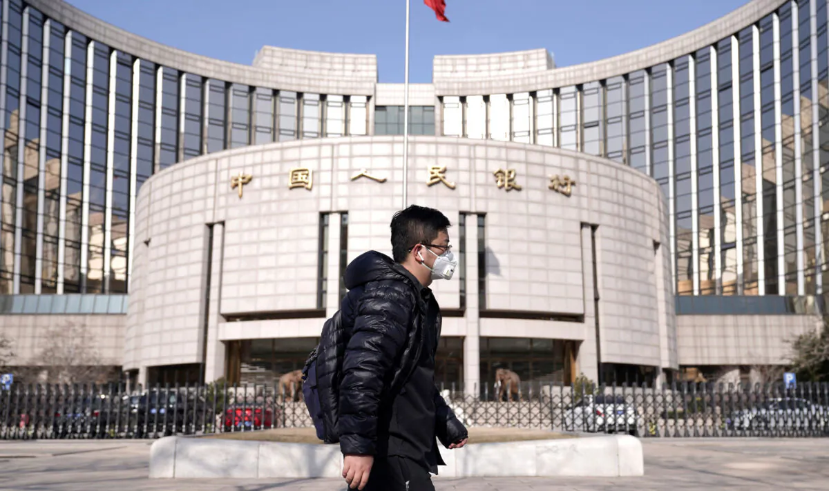 A man wearing a mask walks past the headquarters of the People's Bank of China, the central bank, in Beijing on Feb. 3, 2020. (Jason Lee/Reuters)
