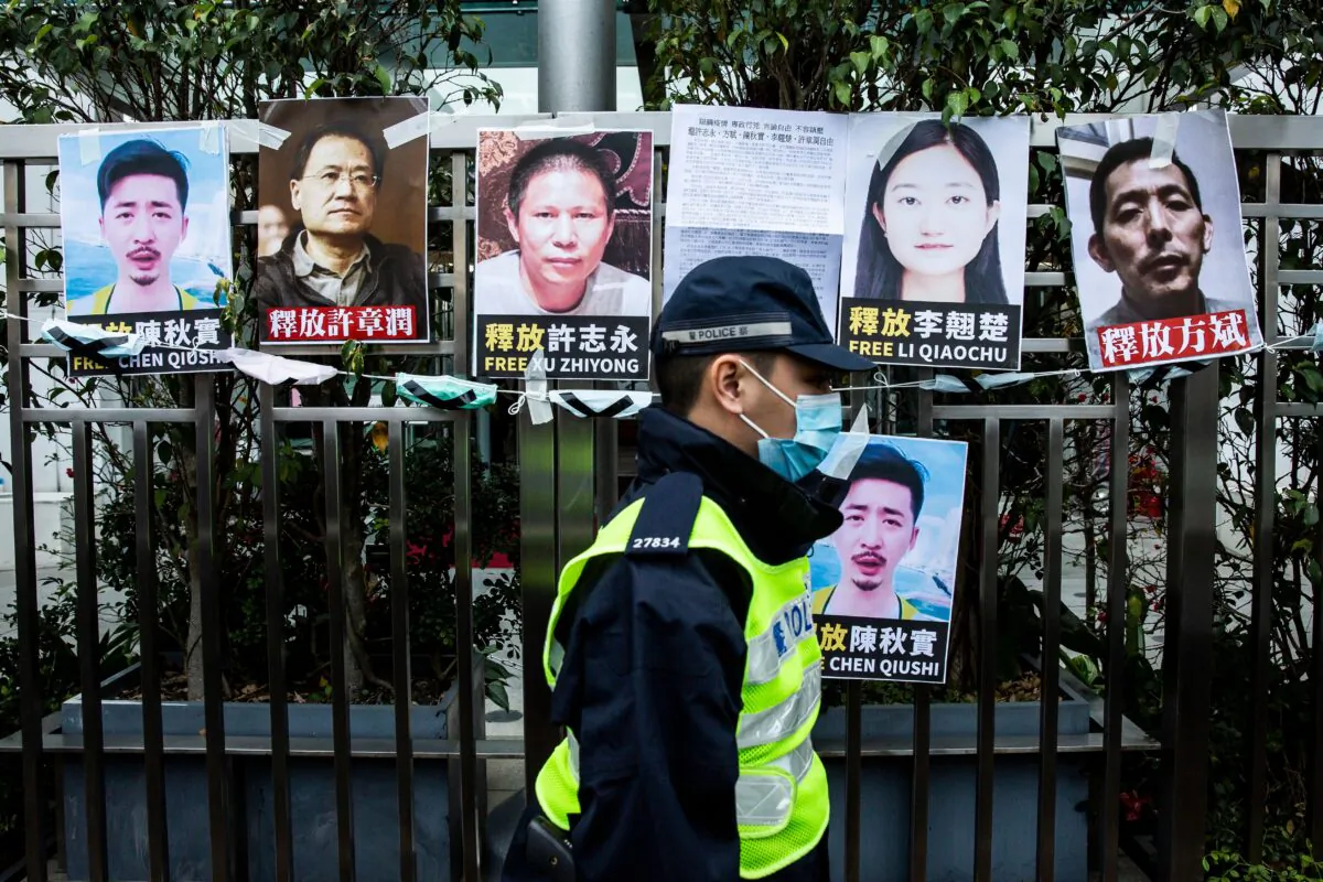 A police officer walks past placards of detained rights activists taped on the fence of the Chinese liaison office, in protest against Beijings detention of prominent anti-corruption activist Xu Zhiyong, in Hong Kong, China, on Feb. 19, 2020.  (Isaac Lawrence/AFP via Getty Images)