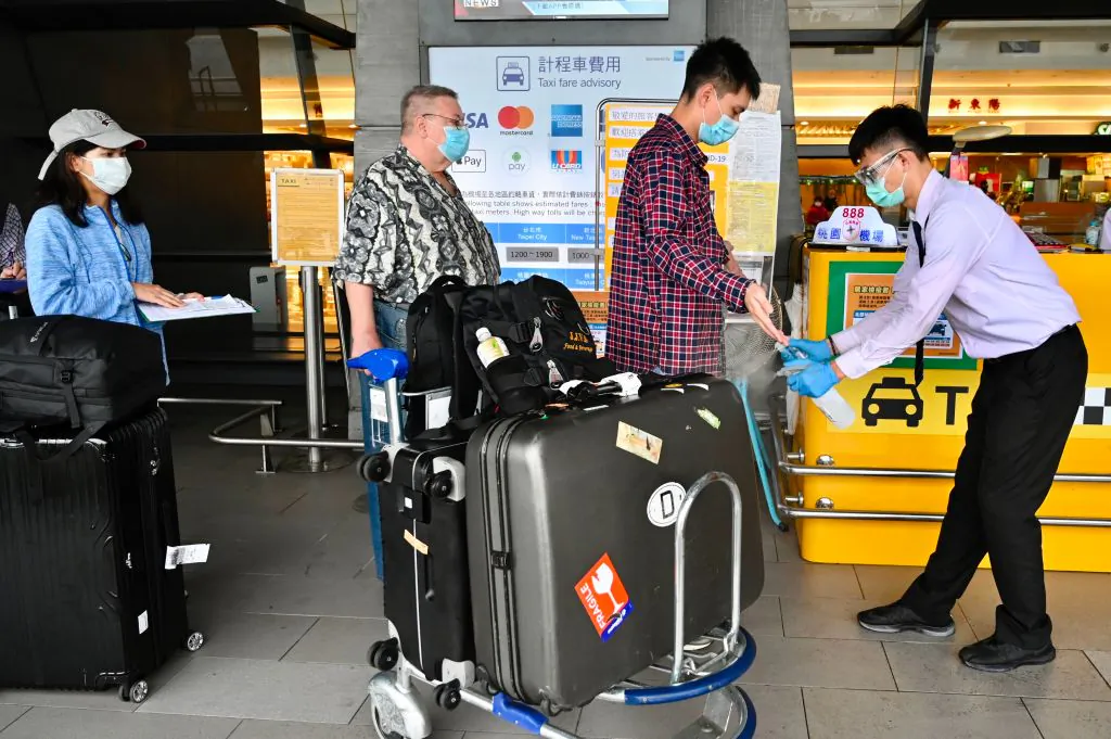 A worker sprays hand sanitizer onto passengers after they arrived at Taoyuan International Airport in Taiwan on March 19, 2020. (Sam Yeh/AFP via Getty Images)