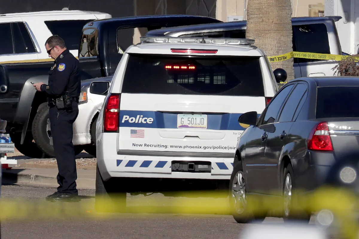 A Phoenix police officer stands outside his vehicle in Phoenix on March 30, 2020. (Matt York/AP Photo)
