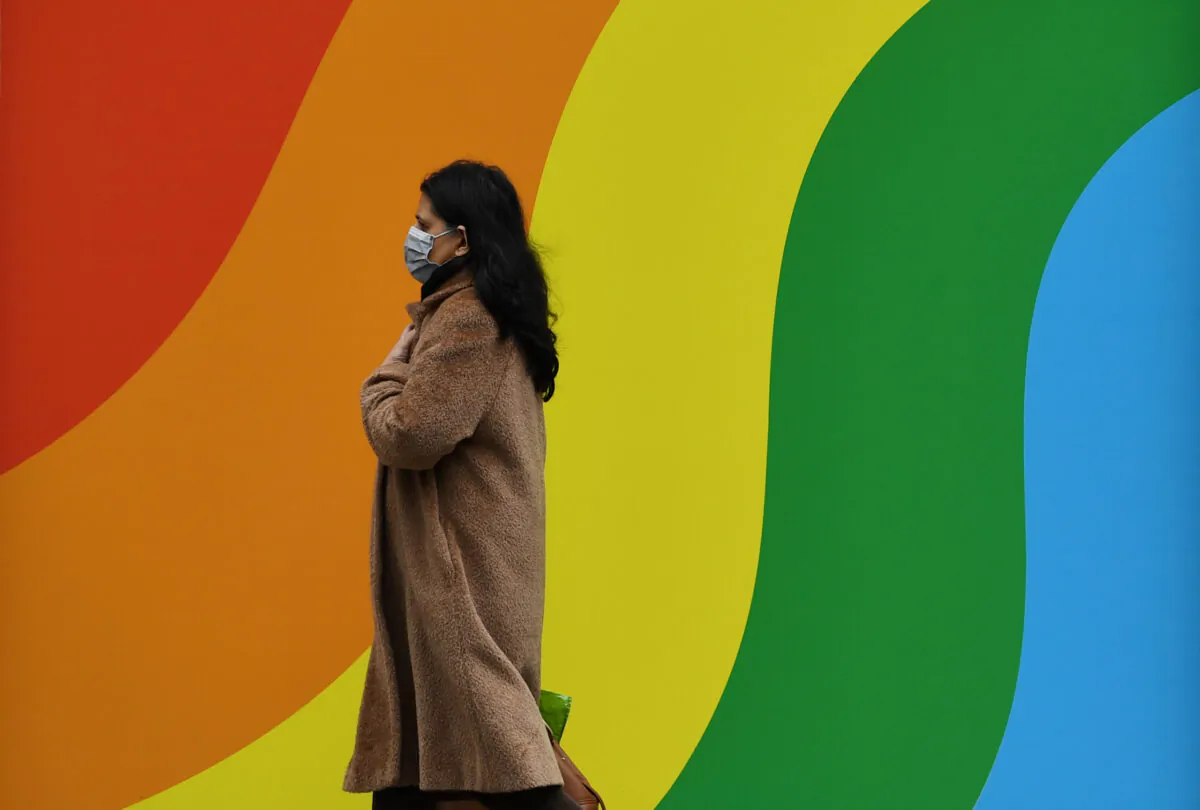 A woman wearing a mask walks past a display in support of the NHS outside Harrods in London, Britain on March 31, 2020. (Dylan Martinez/Reuters)