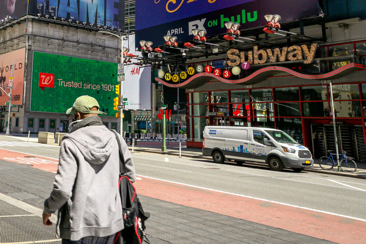 A man walks pass the nearly empty street outside Times Square subway station in New York on April 15, 2020. (Chung I Ho/The Epoch Times)