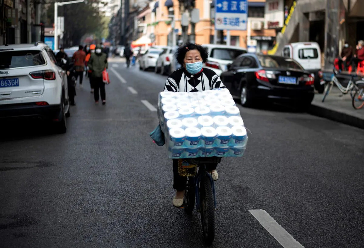 A woman is cycling along a street in Wuhan, China on April 1, 2020. (Photo by NOEL CELIS / AFP) (Photo by NOEL CELIS/AFP via Getty Images)