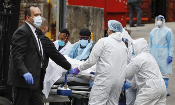 A body wrapped in plastic that was unloaded from a refrigerated truck is handled by medical workers wearing personal protective equipment due to CCP virus concerns at Brooklyn Hospital Center in New York on March 31, 2020. (John Minchillo/AP Photo)