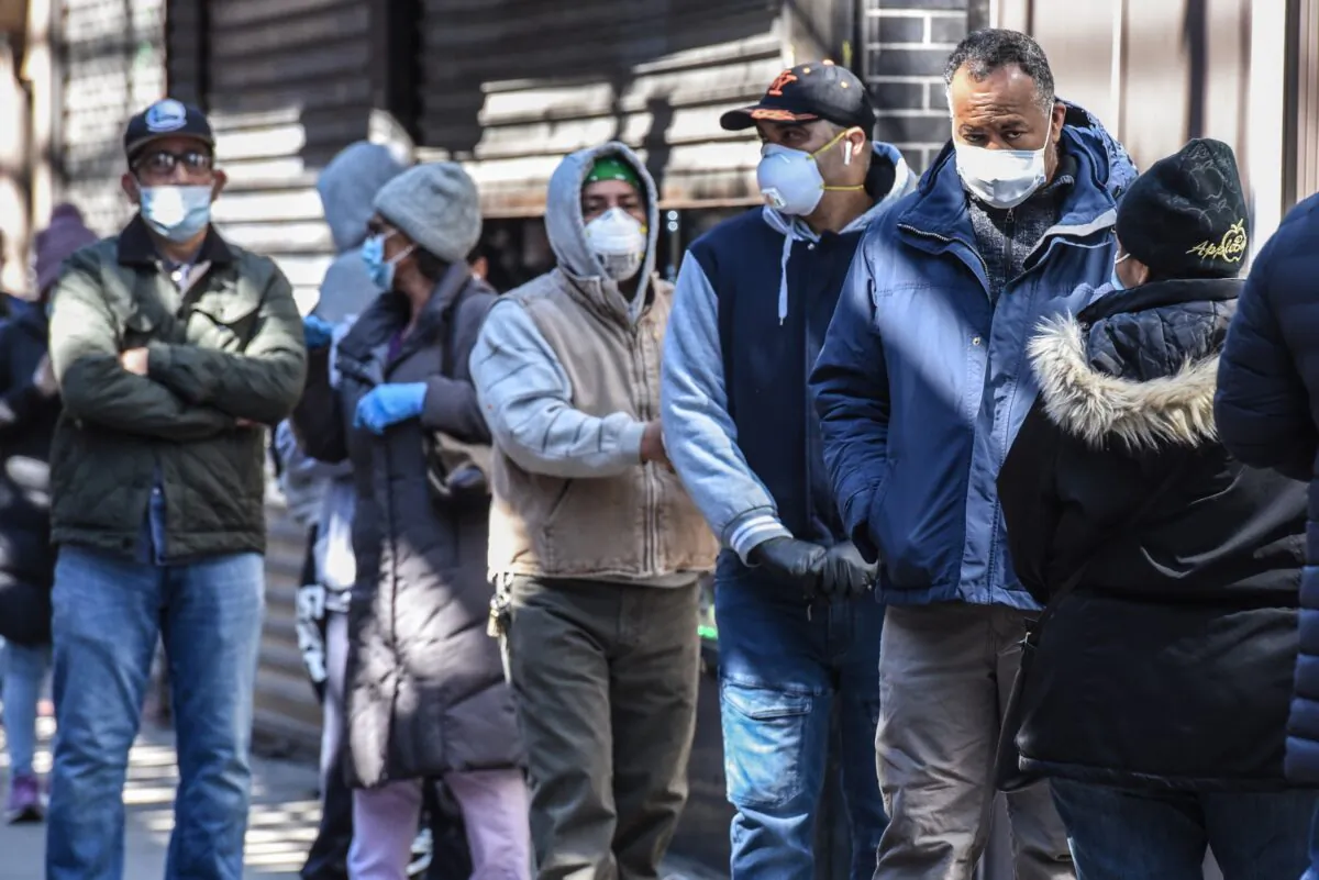 People stand in line while wearing face masks in the Elmhurst neighborhood in New York City on April 1, 2020. (Stephanie Keith/Getty Images)