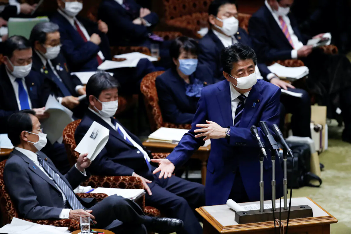 Japan's Prime Minister Shinzo Abe, wearing a protective face mask, gestures next to Japan's Finance Minister Taro Aso during an upper house parliamentary session in Tokyo, Japan on April 1, 2020. (Issei Kato/Reuters)
