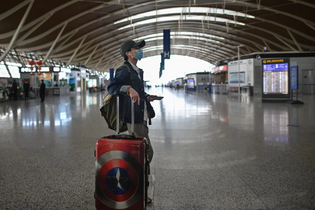 A passenger looks at a screen at Shanghai Pudong International Airport in Shanghai, China on March 19, 2020. (HECTOR RETAMAL/AFP via Getty Images)