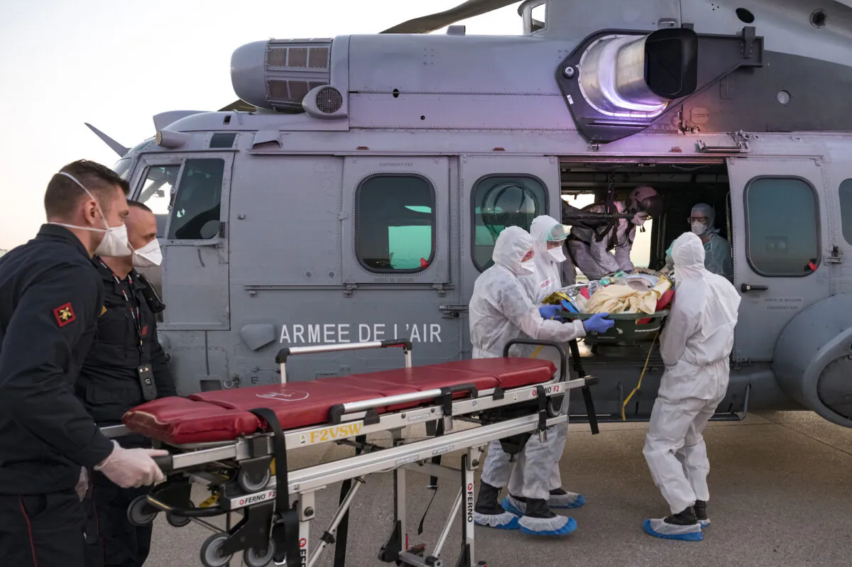 Medics evacuate a COVID-19 patient at an airport near Paris, France, on April 1, 2020. (Julien Fechter/DICOD via AP)