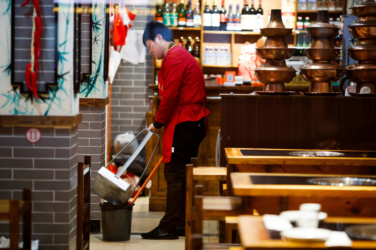 A waiter cleans the floor of a restaurant after closing hours in Beijing, China on Oct. 28, 2019. (Thomas Peter/Reuters)