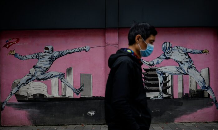 A man wearing a face mask walks past a mural along a street in Wuhan, China's central Hubei province on April 2, 2020. (NOEL CELIS/AFP via Getty Images)