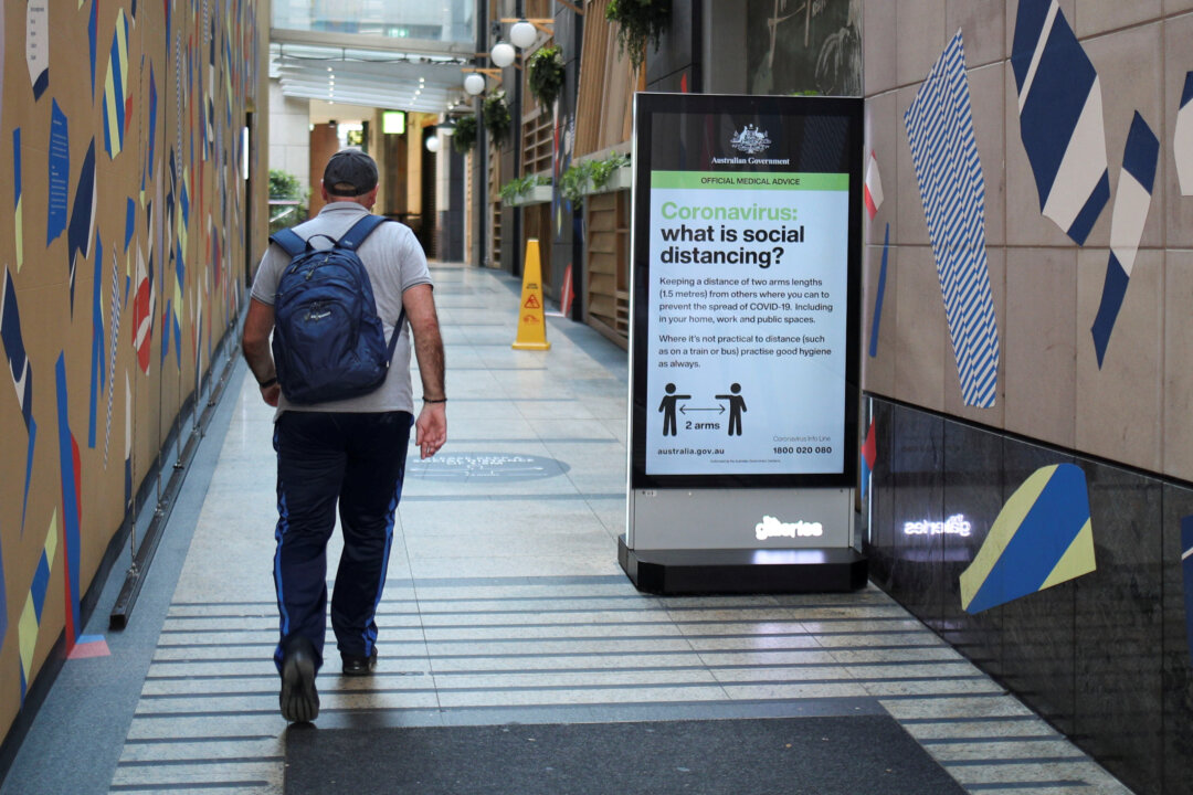 man walks in a corridor near a sign with instructions about the coronavirus social distancing, Sydney, Australia, March 31, 2020.  (Reuters/Loren Elliott)