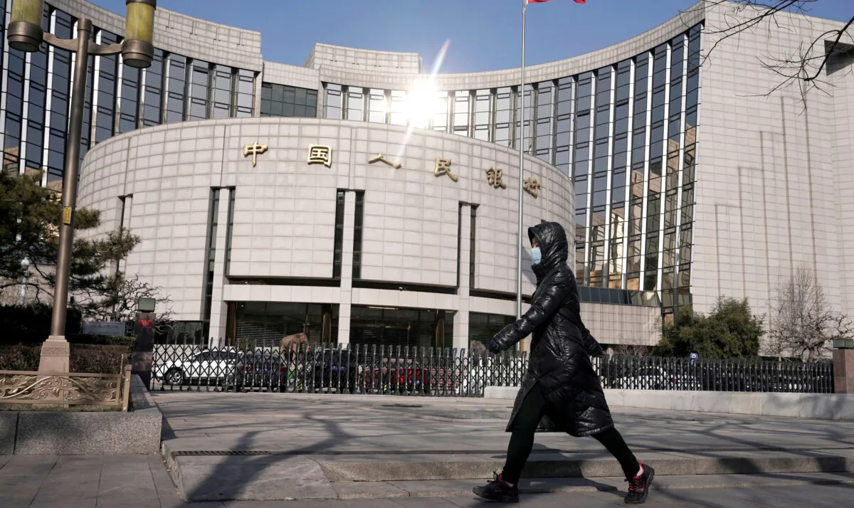 A woman wearing a mask walks past the headquarters of the People's Bank of China, the central bank, in Beijing, China, as the country is hit by an outbreak of the new coronavirus, on Feb. 3, 2020. (Jason Lee/Reuters)