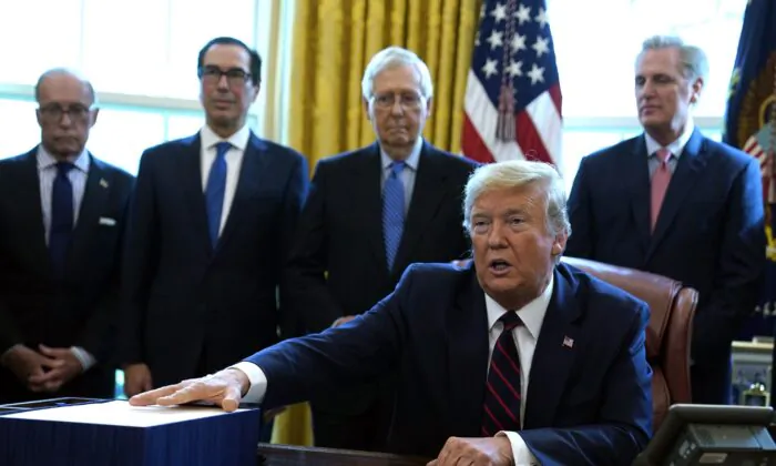 Then-President Donald Trump speaks before he signs the coronavirus stimulus relief package in the Oval Office at the White House in Washington on March 27, 2020. Listening are from left, Larry Kudlow, White House chief economic adviser, Treasury Secretary Steven Mnuchin, Senate Majority Leader Mitch McConnell (R-Ky.), and House Minority Leader Kevin McCarty (R-Calif.). (Evan Vucci/AP Photo)